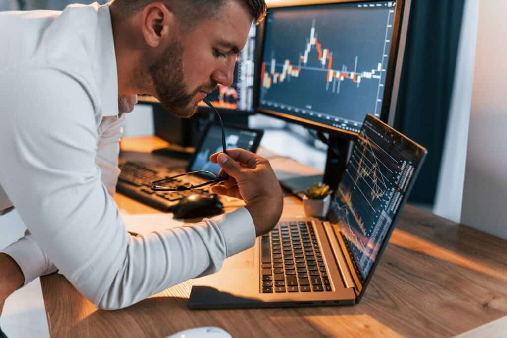 International business. Young man in formal clothes is in office with multiple screens